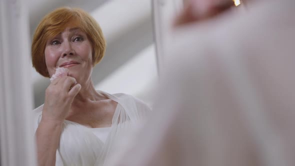 Closeup Reflection of Excited Redhead Senior Bride Touching Face with Flower in Slow Motion Smiling