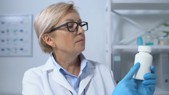 Elderly Female Therapist Showing Vitamins Jar at Camera, Effective Treatment