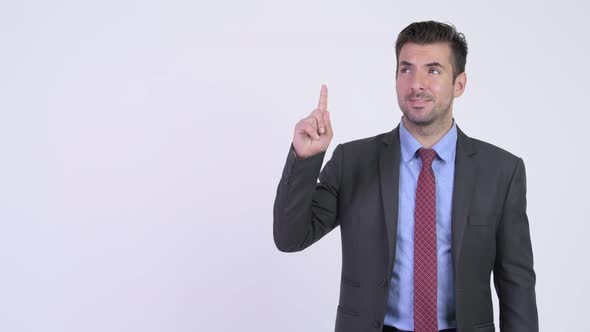 Young Happy Hispanic Businessman Thinking While Pointing Up