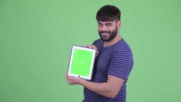 Happy Young Overweight Bearded Indian Man Showing Digital Tablet and Getting Good News