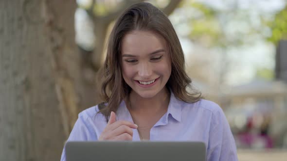 Happy Caucasian Woman in Park Texting on Laptop, Laughing