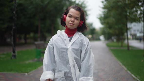 Thoughtful Confident Young Little Woman Walking Outdoors Listening to Music in Headphones