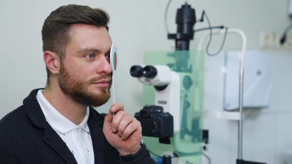 Close-up portrait of man during test on refractometer machine.