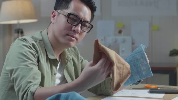 Close Up Of Asian Man Designer With Layout Bond Looking At The Fabric In Hands