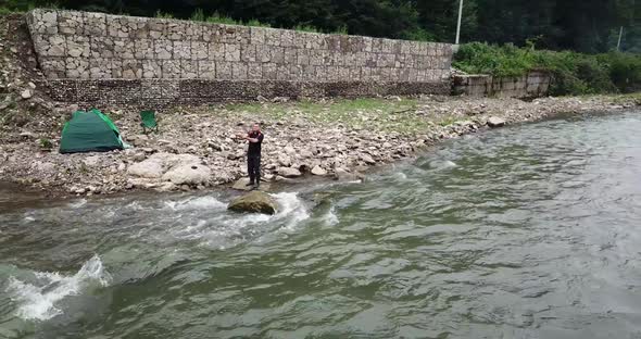 A Male Fisherman Catches Fish on a Stormy Mountain River Spinning Predatory Fish