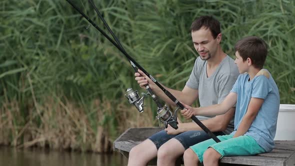 Positive Father and Son Fishing Together on Pond