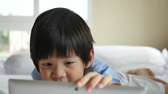 Cute Asian Boy Lying In Bed And Using Laptop On White Bed Slow Motion