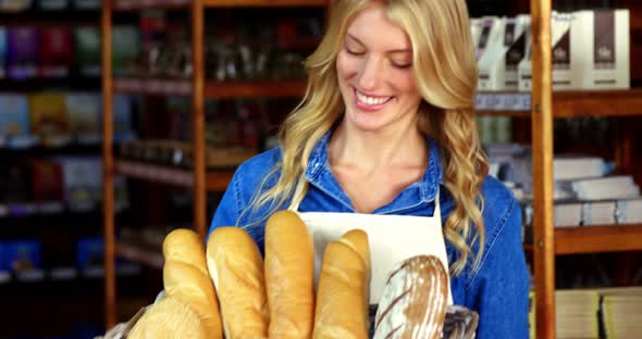 Smiling woman holding a basket of baguettes in organic shop