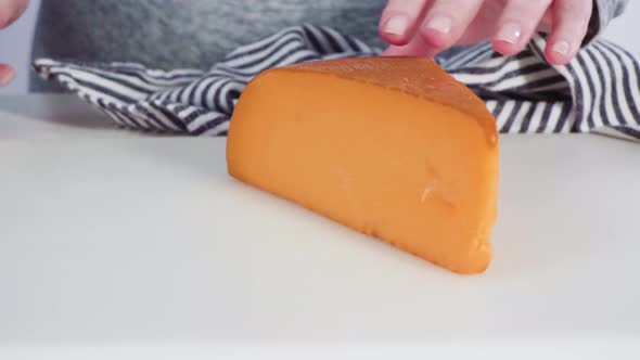 Slicing a large slice of gourmet cheese on a white background.