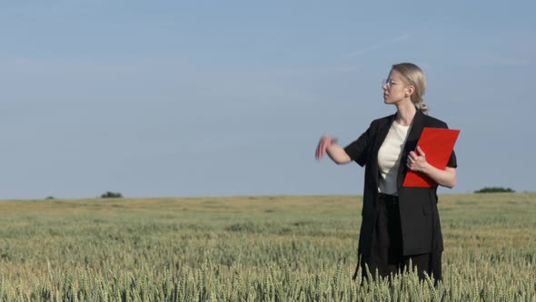 employee of an agricultural firm with notebook checks the quality of wheat in the field