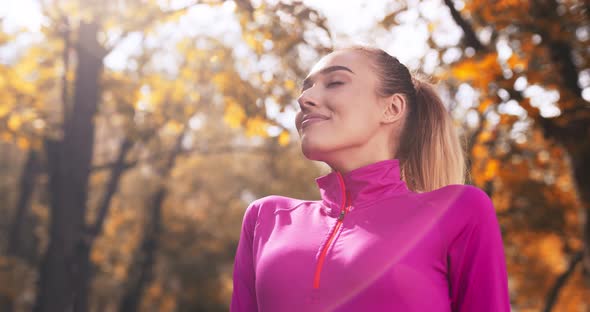 Outdoor Portrait of Happy Blonde Woman Enjoying Sun in Autumn Park