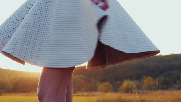 A Woman in a Light Skirt with Slender Legs Turns Around Herself, the Sun Illuminates Her Clothes