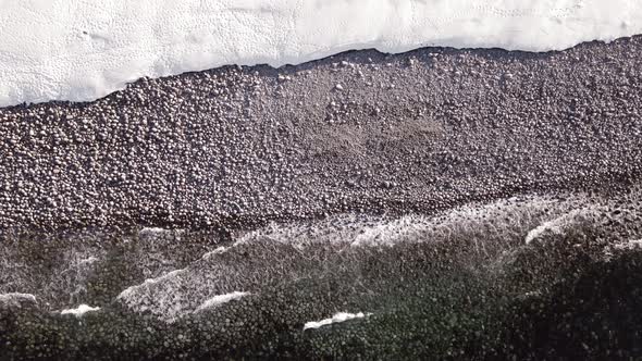 Winter Aerial Flight Top Over Waves Rolling on Artic Ocean Shore with Round Stones Ocean Waves at