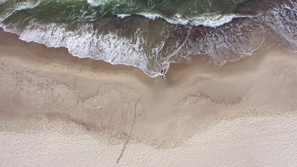 AERIAL: Top View of Couple Walking on a Cloudy Day on Beach with Bare Foots