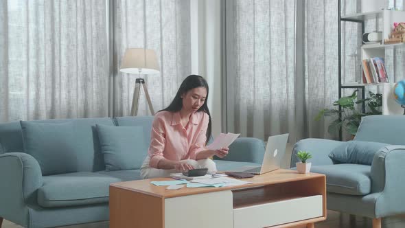 Asian Woman With A Laptop Holding Bill And Calculating Money By Calculator