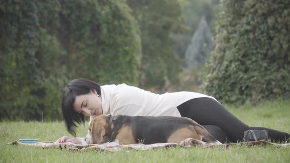 Wide Shot of Happy Relaxed Woman and Dog Lying on Blanket in Spring or Autumn Park