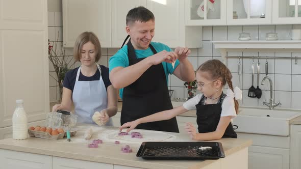 Family of Three Cutting Cookies of Dough at Home