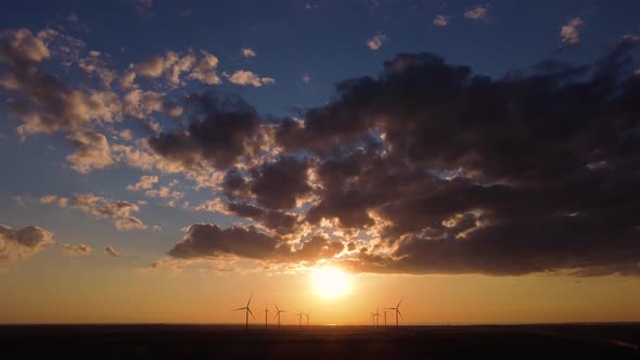 Aerial view of wind power plant on sunset. sea background. 4k drone footage.
