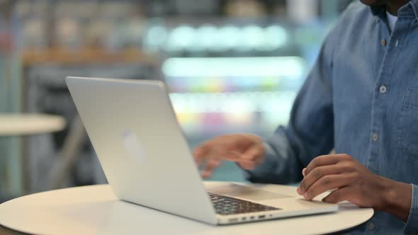 African Man Opening Laptop and Typing in Cafe Close Up