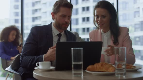 Focused Business People Discussing Marketing Using Laptop Computer in Cafe