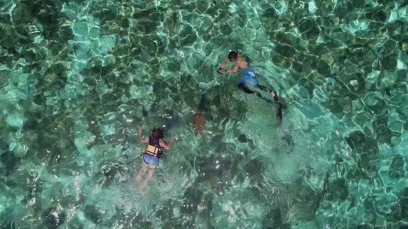 Aerial view of two people snorkeling with turtle in Panagsama Beach, Philippines.