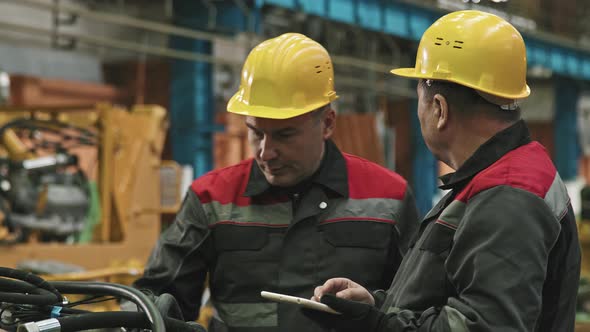 Plant Workers With Tablet Talking At Assembly Shop