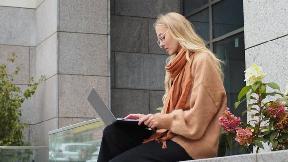Pensive Female Freelancer Sitting Outdoors Near City Building Working on Laptop Successful Business