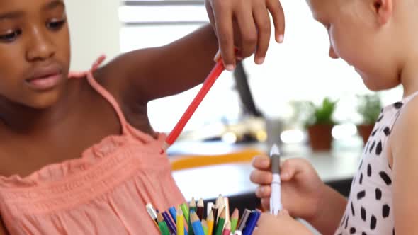 Schoolgirls picking up pencil from pen holder