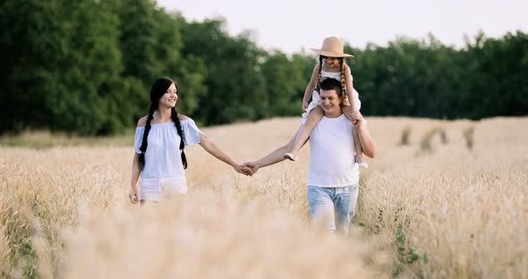 A Little Girl Walks the Wheat Field with Her Parents Slow Motion