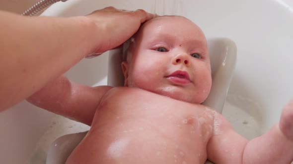 Mother Bathes a Small Child in a Bath