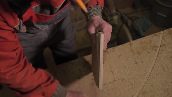 Carpenter Stands Behind the Workplace Polishes with Sandpaper Processes Wood