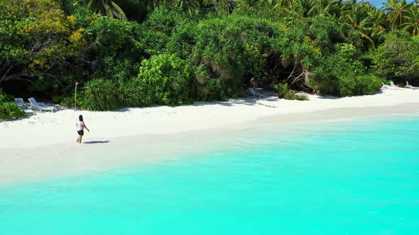 Woman suntans on tropical shore beach break by shallow sea with white sand background of the Maldive