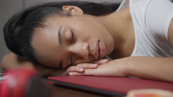 Closeup Face of Fatigued African American Young Woman Sleeping on Table in Home Office