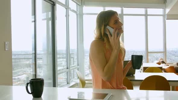 Woman talking on mobile phone while having coffee