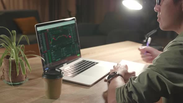 Man Trader Sitting In A Wheelchair Using Laptop Computer And Note In Book For Cryptocurrency