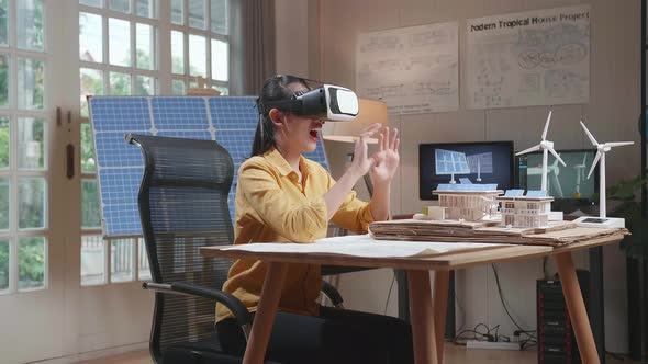 Woman Working With A Model Of Small House Roof Solar Panel Wearing VR And Showing Touching Gesture