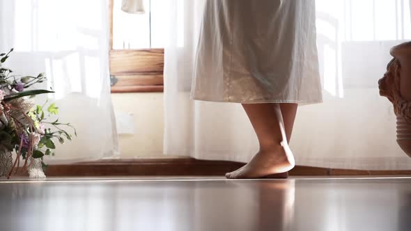 Barefoot anonymous woman standing near window