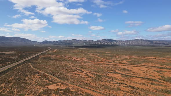 Drone aerial moving left of renewable energy wind power farm in desert country Australia on a sunny