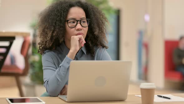 Young African Woman Thinking Using Laptop