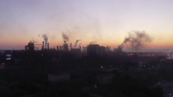 Silhouettes of blast furnaces against the sky before dawn.