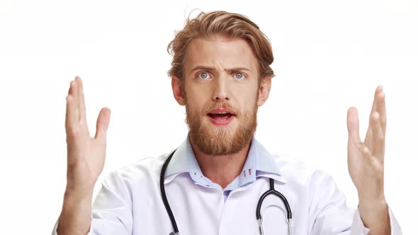 Annoyed Young Caucasian Male Doctor with Light Beard and Blue Eyes Screaming Why at Camera on White