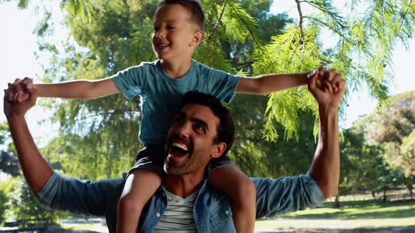 Father carrying son on his shoulders in park