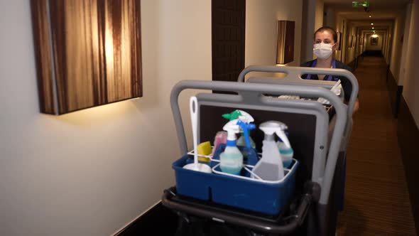 Housemaid with Trolley Walking Down Hotel Corridor