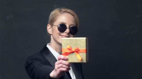 smiling businesswoman in a classic business suit and sunglasses gives a gift