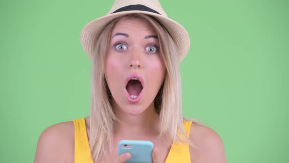 Happy Young Blonde Tourist Woman Using Phone and Looking Surprised