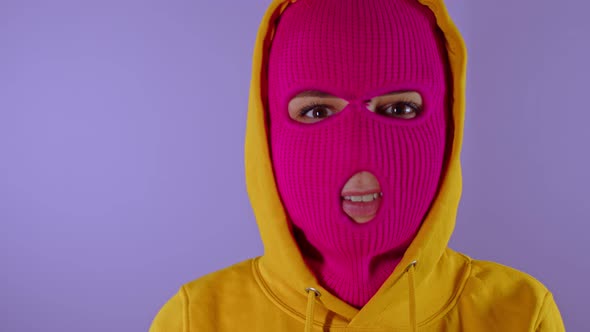 Unrecognizable Woman in Pink Balaclava Smiles on Purple Background