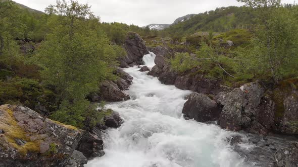 Beautiful fast flowing mountain river cascading down rocky gorge, aerial dolly