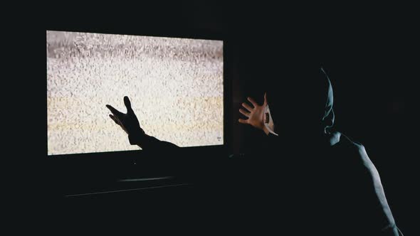 Silhouette Man in Hood and Medical Mask Watching TV Interference with Hands Up