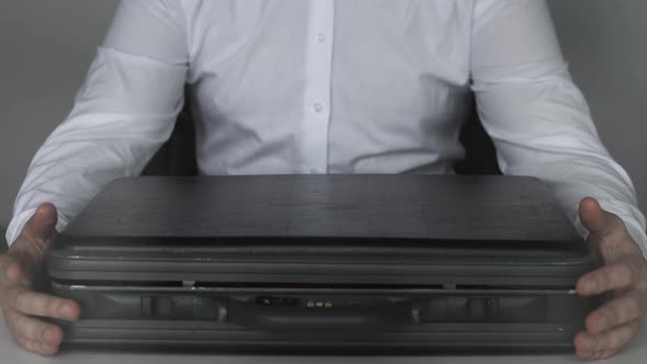 Businessman Sits with Closed Case Full of American Dollars Money