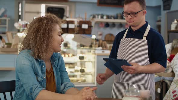 Caucasian waiter man with down syndrome discussing menu with the client. Shot with RED helium camera